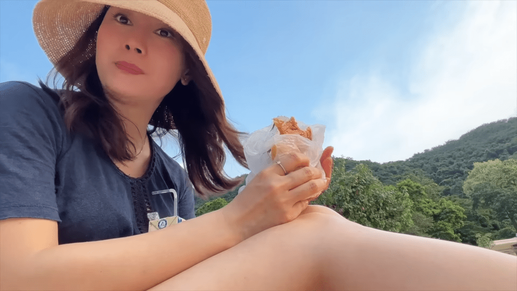 袁嘉敏只独自坐在沙滩上食包饮豆奶。