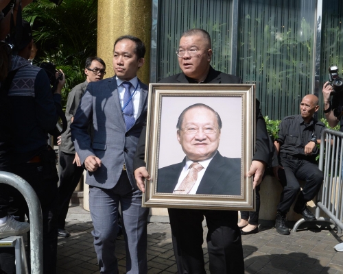 大殮儀式後，金庸兒子查傳倜手持父親遺照步出殯儀館。 