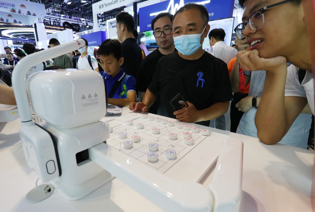 參觀者在2023世界人工智能大會展會現場與商湯元蘿蔔AI下棋機器人對弈。新華社