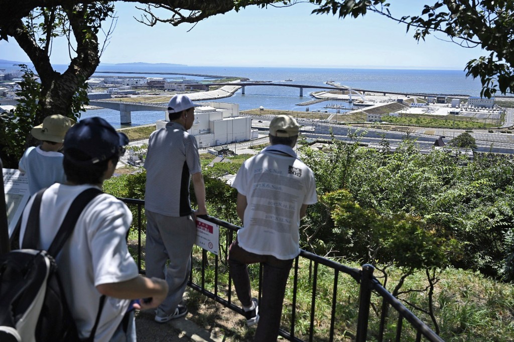 疏散到日和山的居民向日本北部宮城縣石卷市的大海望去。 美聯社