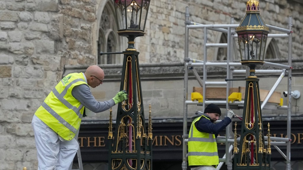 英王查理斯三世的加冕典禮在即，工人補油粉飾白金漢宮外的街燈。 美聯社