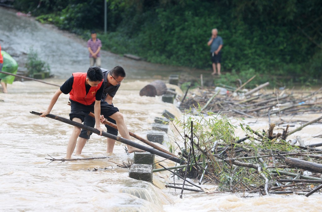 在廣西柳州市融安縣大將鎮大將社區逢村屯，黨員幹部冒雨清理大橋上的雜物。 新華社
