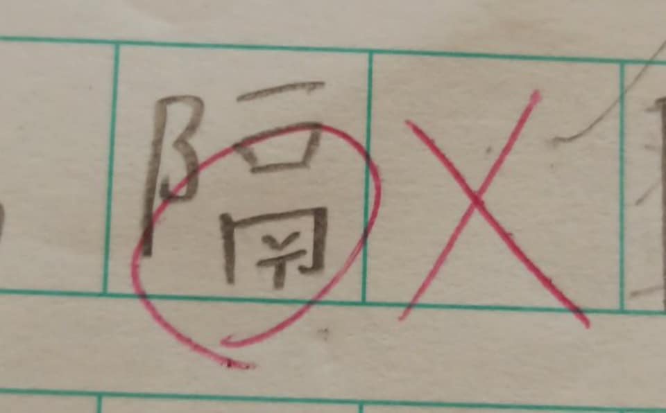 有家长在网上发贴文,对子女书写的「隔」字被红笔圈起,并打交叉感到不解。(图片来源:Facebook@不愿小朋友成为功课奴隶) 有家长在网上发贴文,对子女书写的「隔」字被红笔圈起,并打交叉感到不解。(图片来源:Facebook@不愿小朋友成为功课奴隶)