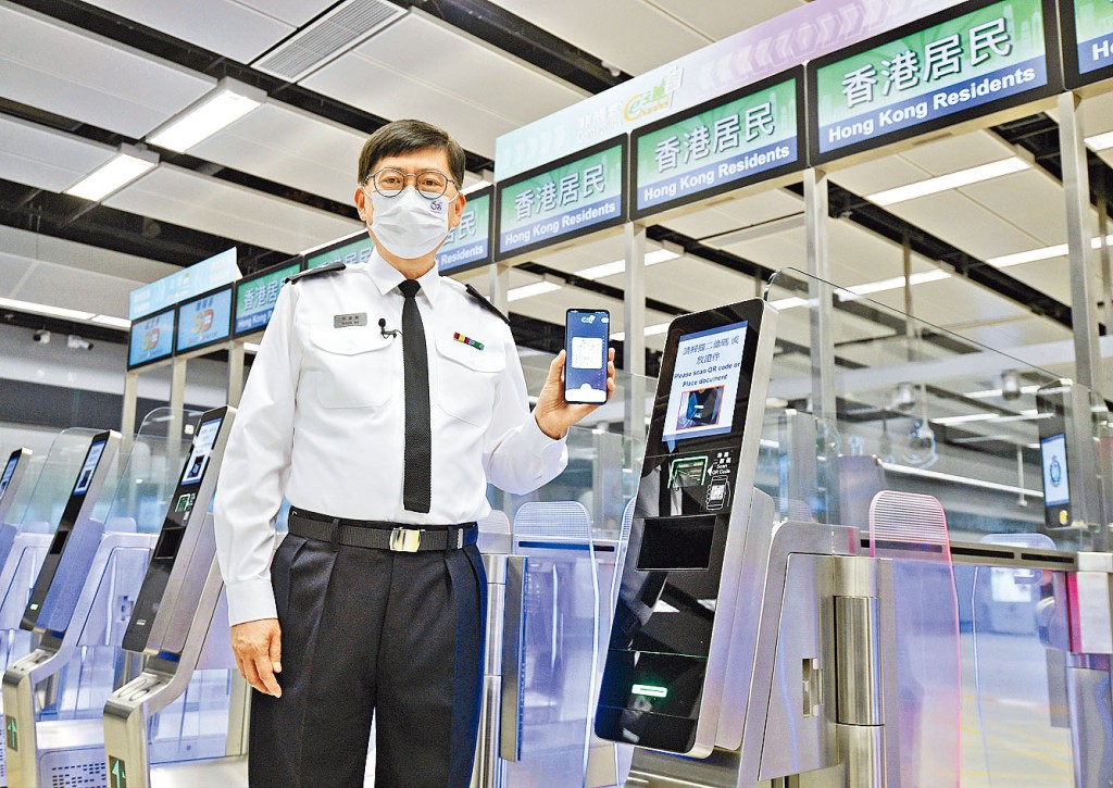 入境处助理处长何家荣安装「智方便」登记后，以手机显示的加密二维码朝向闸机扫描器扫描。