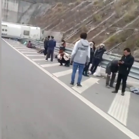 重慶旅遊巴高速公路翻側，傷者在馬路旁等待救援。