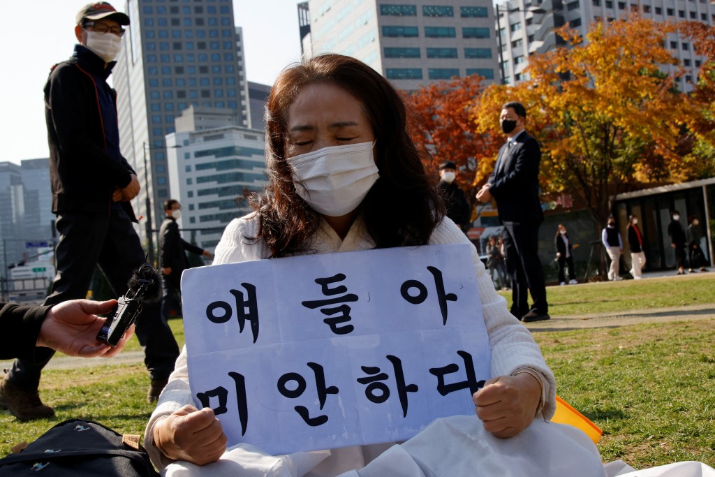 一名婦女在韓國首爾市政廳廣場的集體紀念祭壇前舉著「對不起」的標語。路透