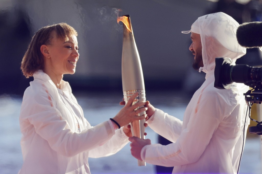 法國殘奧會運動員南特寧·科簿塔（左）在法國南部馬賽舉行的火炬抵達儀式上將奧運火炬傳遞給法國說唱藝術家朱爾。 AP