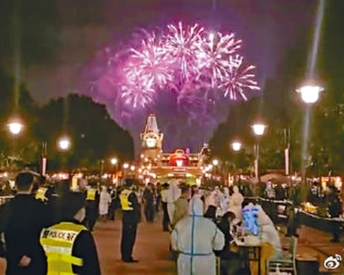 上海迪士尼公園內，防疫人員在煙花下，為遊客核酸檢測。