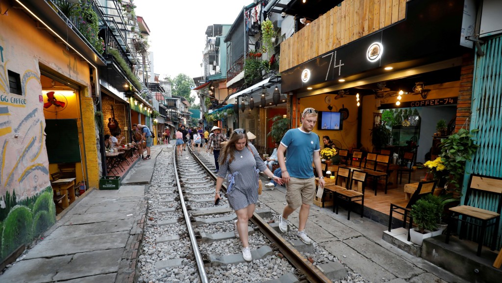 外國遊客走在「火車街」路軌上，兩旁咖啡店林立。 路透社