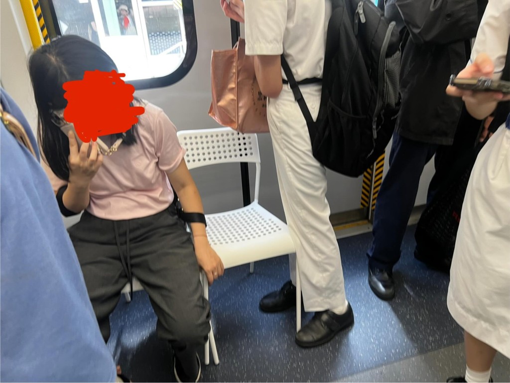 相中正拿著手機說話的長髮女乘客，疑似帶 同兩張白色疏窿膠椅乘搭港鐵，並在車廂的 門口位置平放兩張椅子，自己坐一張，另一 張空凳則用手扶著。當時車廂內站有多名乘 客，包括企於椅子旁的一名學生哥。Threads截圖