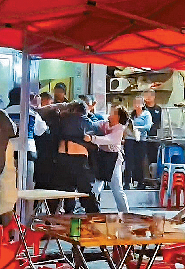 身穿围裙相信为食肆职员的男子被人袭击，女子上前将遇袭男子拉开。