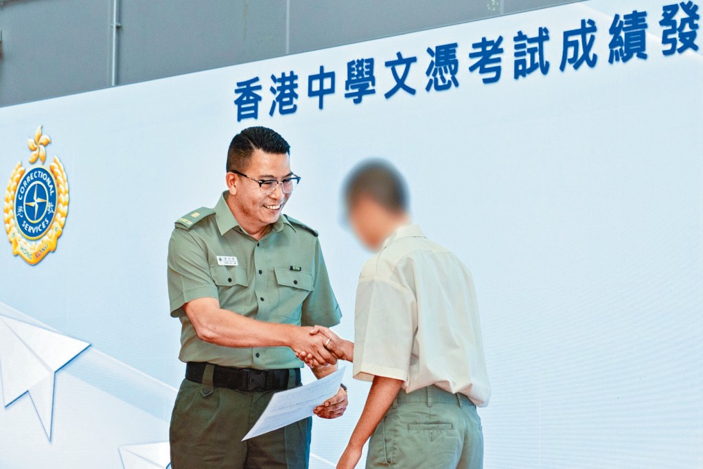 沙咀惩教所监督潘浩霖向其中一名考生颁发成绩通知书。