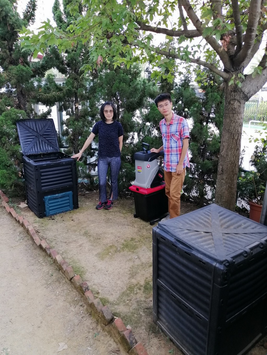 羅敏儀(左)與許信揚(右)指住宅回收園林廢物用作「就地堆肥」的所佔空間不多,只需用上數個堆肥箱及碎枝機等器材。THEi提供圖片