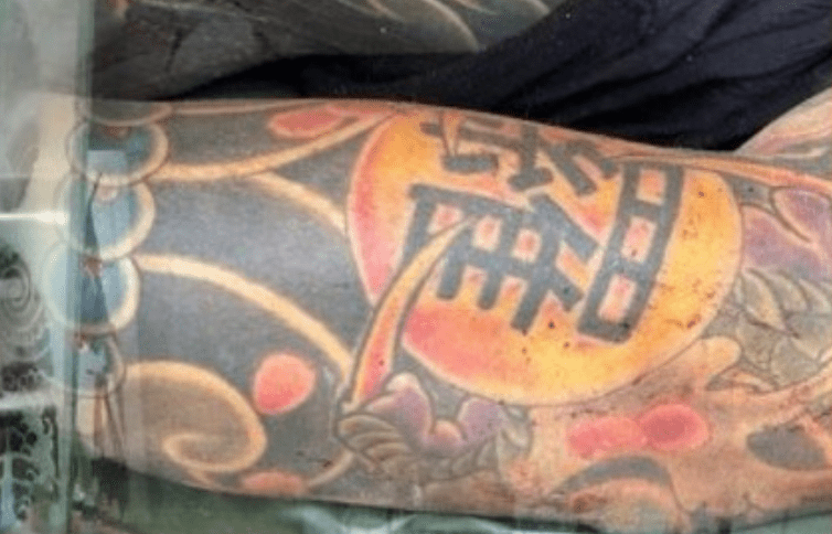 尸体上全身布满不同图案的刺青，其中手臂上刺有一个繁体的「罗」字。泰国电视新闻截图