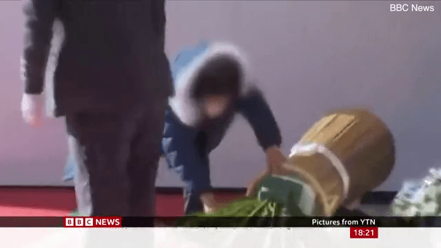 罹難者母親俯身拿著花牌的花朵。BBC新聞截圖