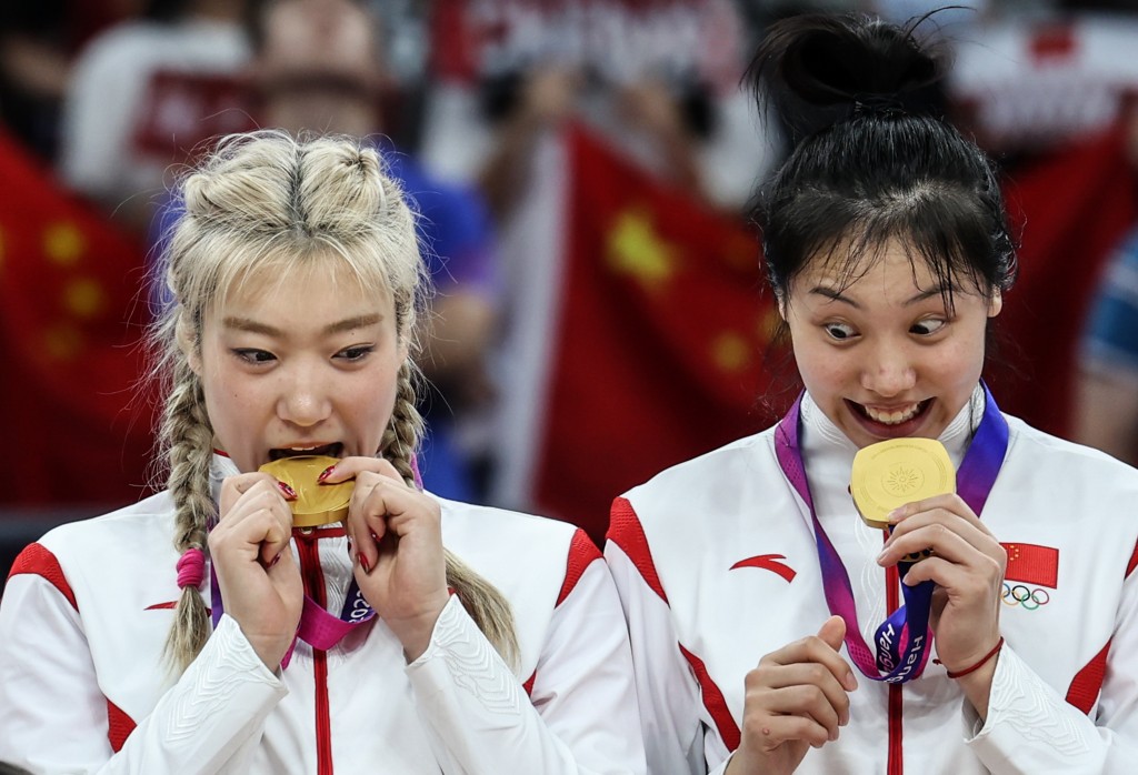 中國隊球員李夢（左）和張茹在頒獎儀式上「咬金牌」。新華社