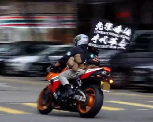 唐英傑於去年七月一日在灣仔駕駛電單車，車上插着兩枝寫有「光復香港，時代革命」口號的旗幟。資料圖片