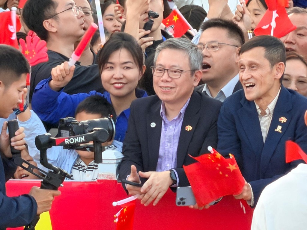 香港科技園公司行政總裁黃秉修（左）及中大副校長（外務）姜里文（右）手持國旗及區旗在「頭排」等候航天員出征。郭詠欣攝