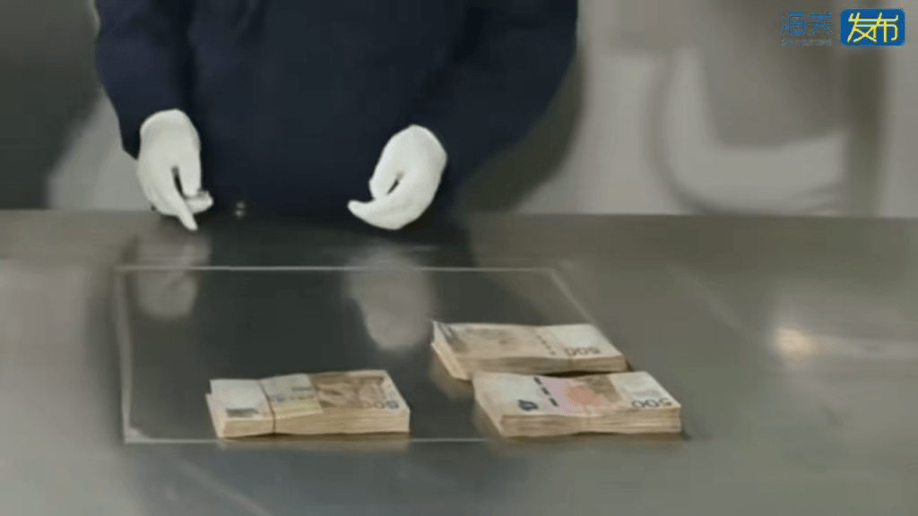 海關關員點算現金數量。海關發布