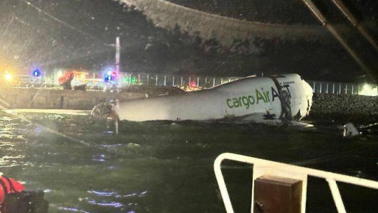 涉事貨機逾半機身浮於水面,機頭擱在岸邊。 涉事貨機逾半機身浮於水面,機頭擱在岸邊。