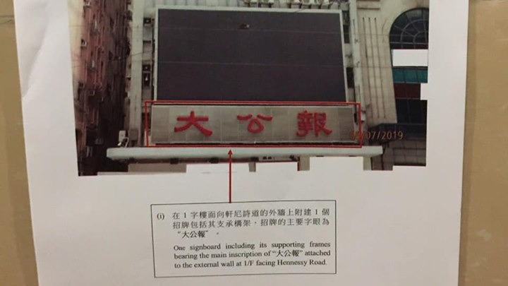 屋宇署派員到灣仔國華大樓張貼命令,促業主於30日內拆除「大公報」違例招牌。 楊雪盈fb圖