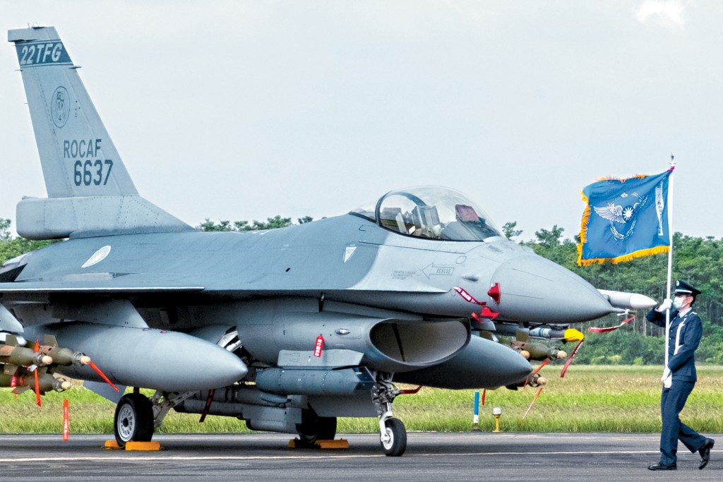 一名台灣空軍旗手走過一架服役的美製F-16V戰機。