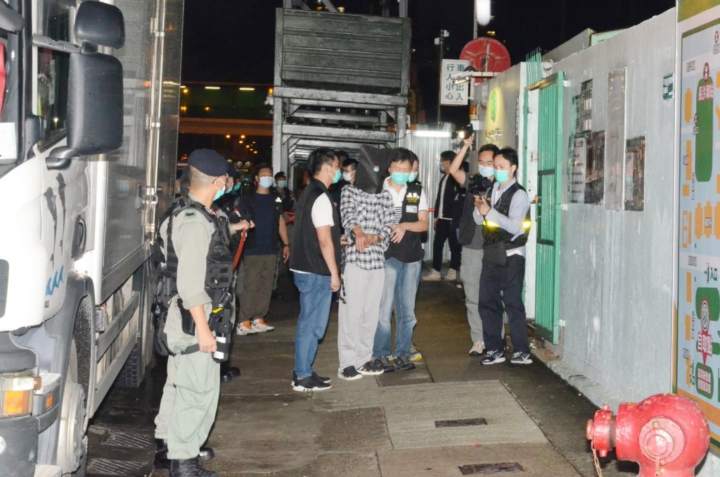 警方押解其中一名疑犯到涉事地點重組案情。