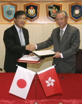 時任保安局局長李少光（右）於2008年與日本駐港總領事及大使交換有關刑事事宜相互法律協助協定的文本。資料圖片