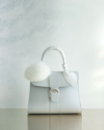 Brillant手袋的手挽飾以白色小牛皮飾帶包裹，並綴以狐毛Pom Pom球形裝飾。
