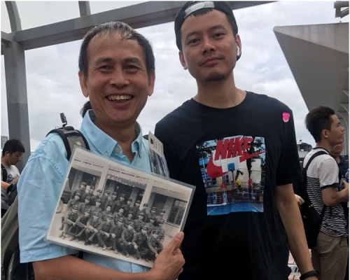 拿著當兵舊相的賴先生(左)期待與解放軍拍照,右為其子。