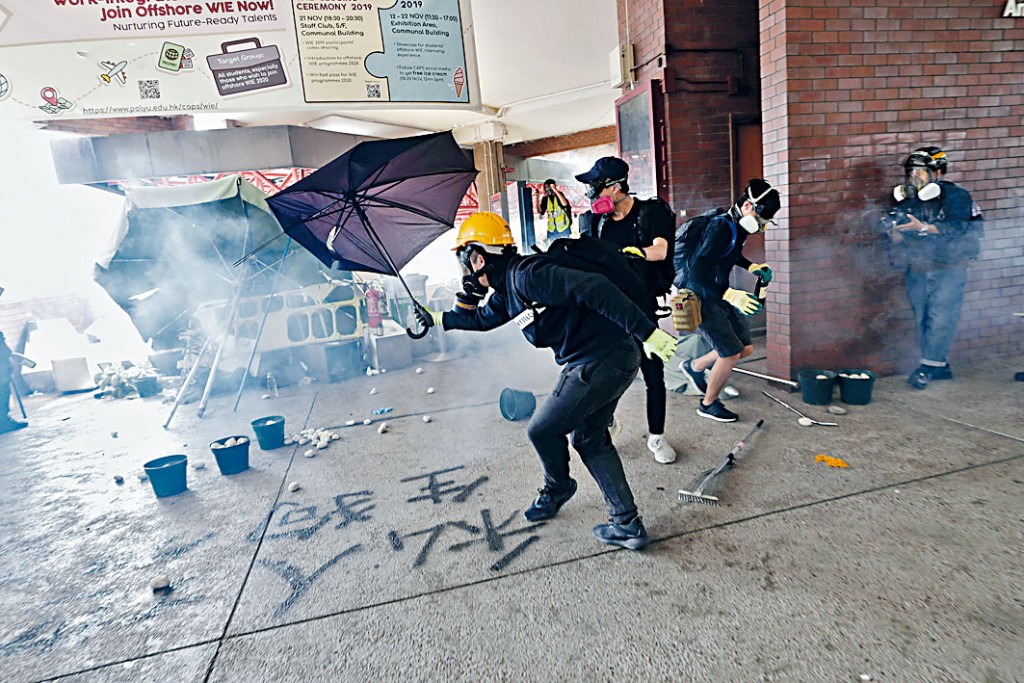 理大事件中，示威者用伞挡催泪弹。