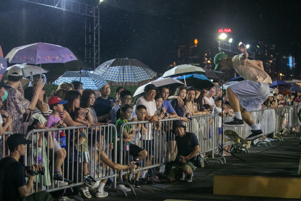 场地间中落起毛毛雨，市民撑伞观看滑板比赛。丹尼尔摄