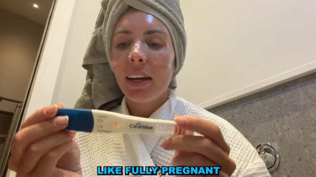 她敷著面膜對鏡頭展示驗孕棒，顯示一條明顯紅線與一條淡粉色線，並強調「我肯定懷孕了」。（YouTube@Bonnie Blue）