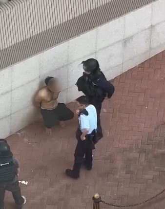 疑兇被反鎖雙手蹲在路旁。網片截圖