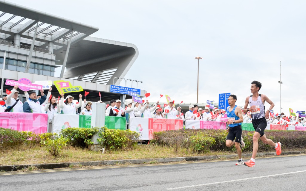 男子組參賽選手跑經深圳灣口岸，打氣隊伍在旁為運動員打氣。政府新聞處