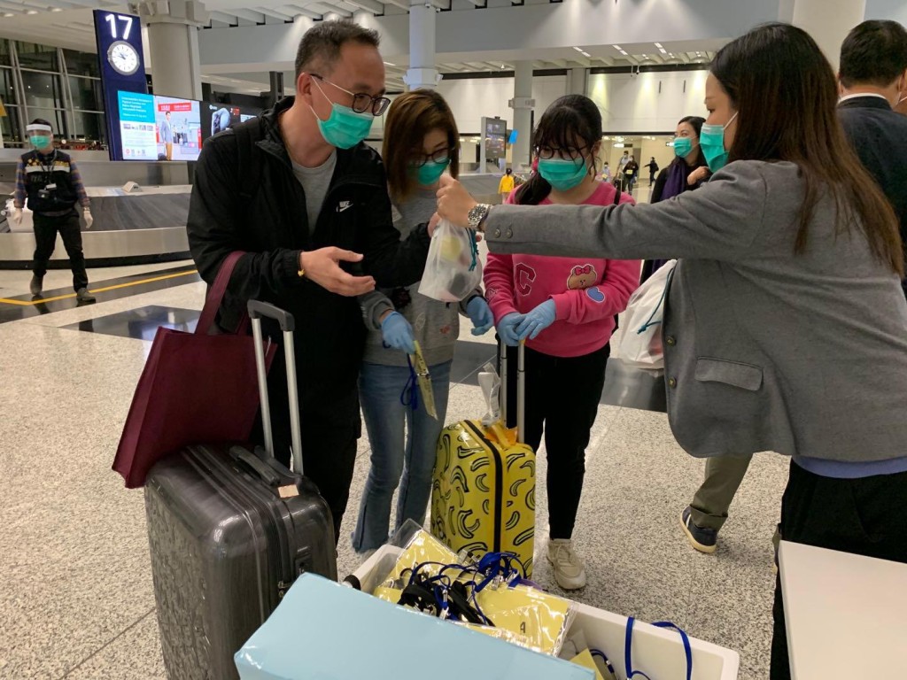 港人到達香港機場後，入境處職員為他們派發由航空公司提供的食物包。讀者提供