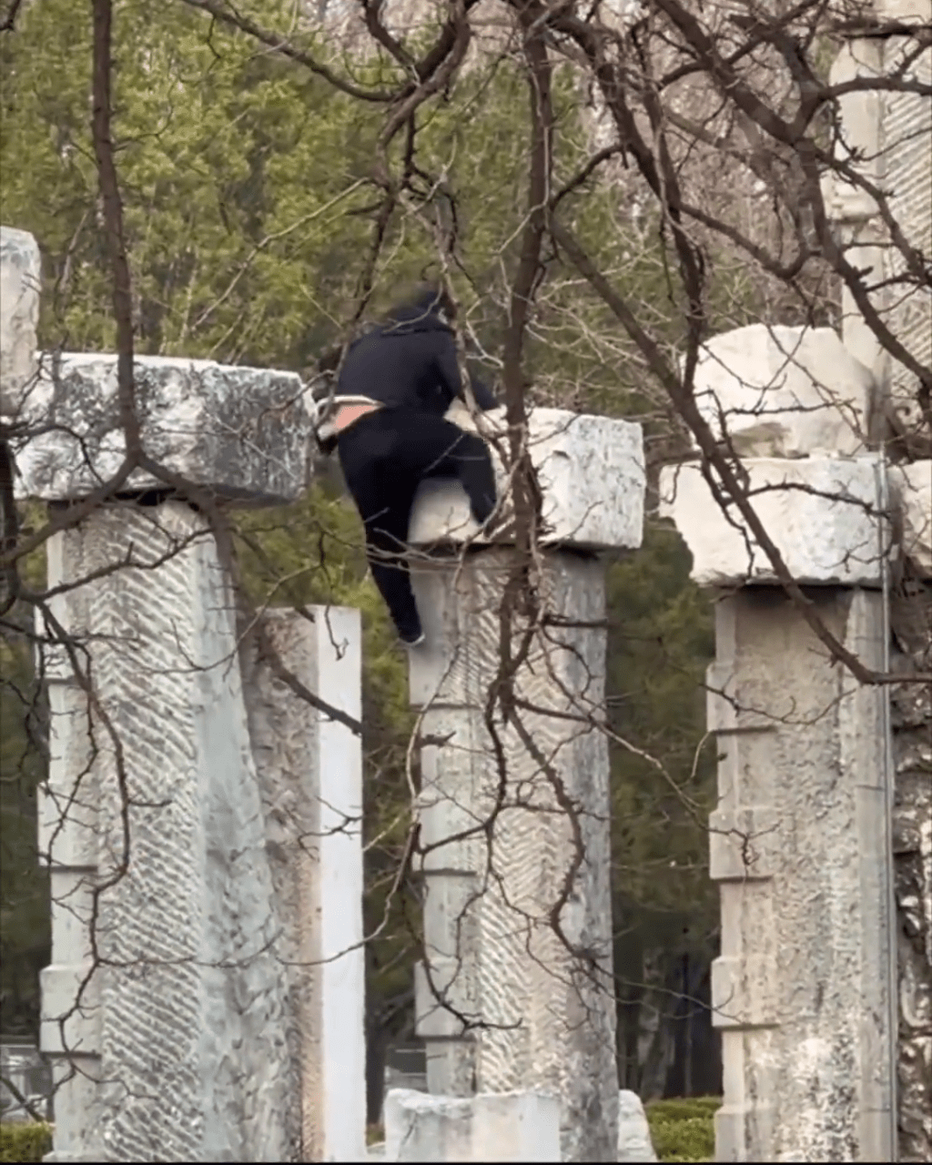 男子在攀爬遺址建築，甚為吃力。