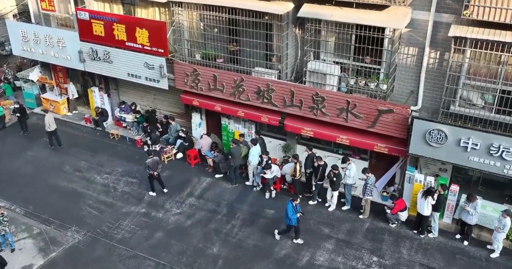 「晓华理发」店外，大批民众排队等候剪发。影片截图