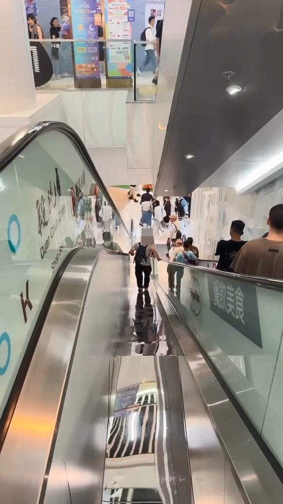 男子翻越玻璃欄杆,爬落扶手電梯中間的銀色蓋板,之後沿著蓋板慢慢爬行到下一層。Threads@showerrrjun片段截圖 男子翻越玻璃欄杆,爬落扶手電梯中間的銀色蓋板,之後沿著蓋板慢慢爬行到下一層。Threads@showerrrjun片段截圖