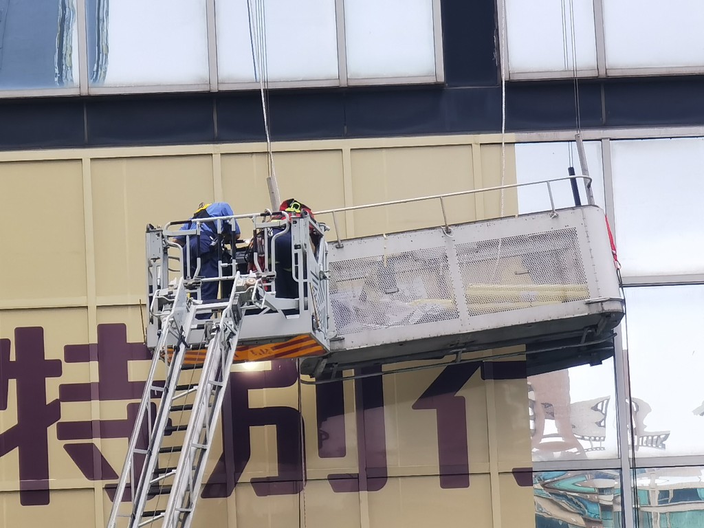 两名工人当时在吊船上处理大楼外墙的海报，其间吊船突然向右倾侧。