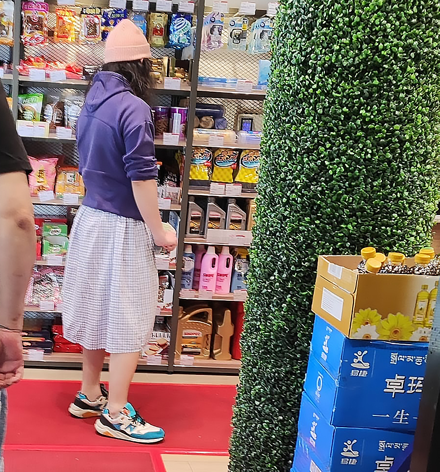 相中的哥身處大埔一個加油站內的便利店，他頭戴冷帽，身穿紫色外套，下身則穿著一條格仔裙，腳著運動鞋。