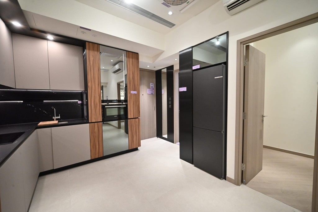 單位採開放式廚房設計，曲尺形廚櫃用上卡其色廚櫃板面，配以黑色枱面及牆身，相當型格。
