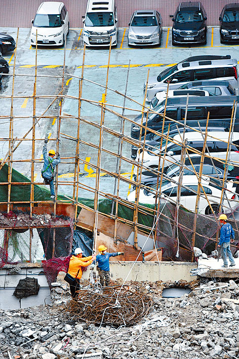 地盤工人用繩索把傾側棚架固定再行施工。
