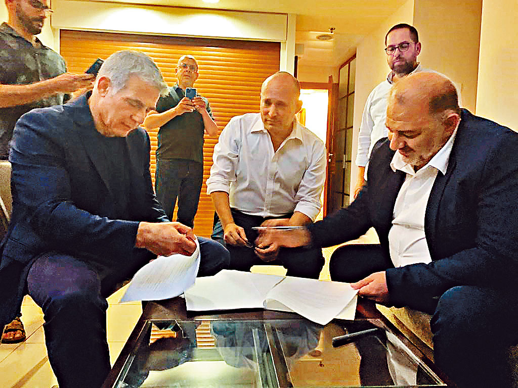 ■有望輪流擔任以色列總理的拉皮德（左）和貝內特（中），與聯合阿拉伯黨領袖阿巴斯，周三在特拉維夫簽署合組政府協議。