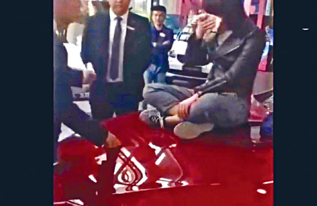女車主坐在引擎蓋上哭訴維權。