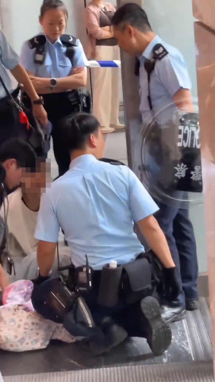 女子被制服後一度坐在地上,雙手被鎖上手銬。 女子被制服後一度坐在地上,雙手被鎖上手銬。