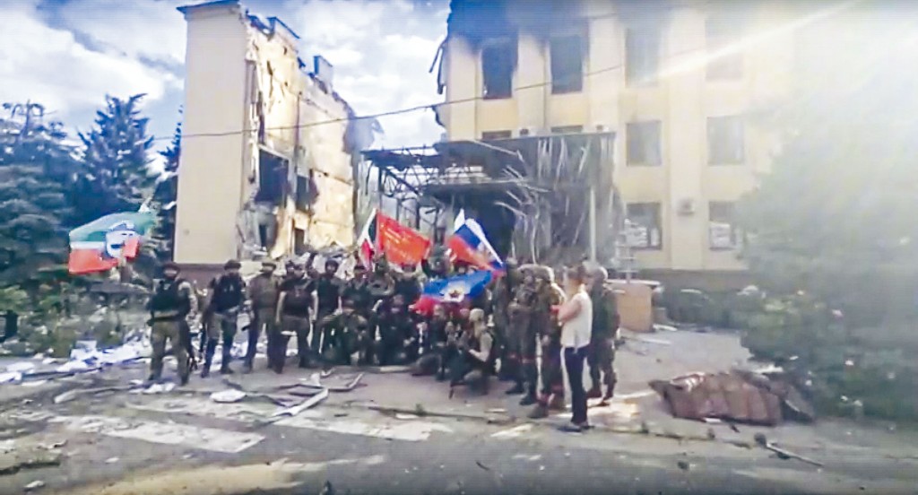 俄軍與車臣士兵上周六在烏克蘭東部利西昌斯克市一座毀爛建築物前,揮舞俄國和車臣共和國旗幟。