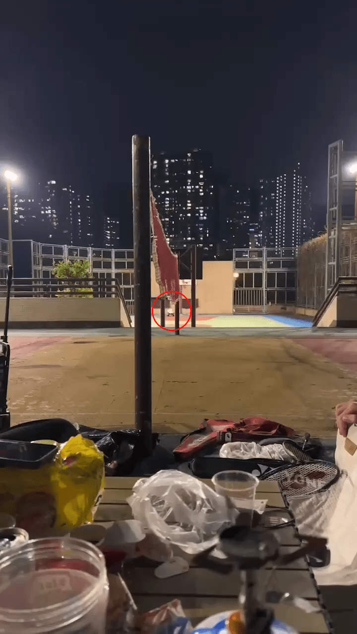 影片在晚上拍摄，在一个露天篮球场，旁边有人在打羽毛球。