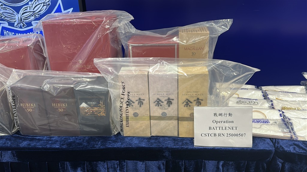 警方展示涉案財物，包括名錶、現金及名酒。劉漢權攝