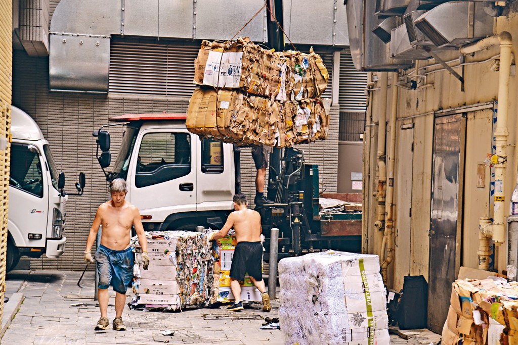 灣仔大王東街一間廢紙回收商接收廢紙後，便立即紮起廢紙再吊起運上車。